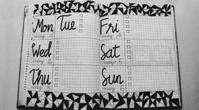 white and black weekly planner on gray surface